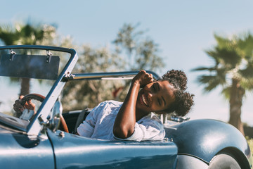 Black woman driving a vintage convertible car