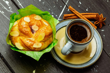 coffee with cinnamon and cake on a black wooden table.