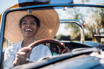Black woman driving a vintage convertible car