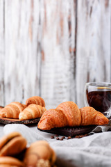croissants in wooden plates with coffee on a light background