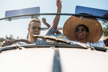 Multiracial couple in a convertible vintage car