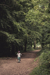 Fototapeta premium Young girl riding bike through woodland