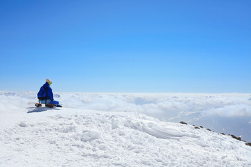 Fototapeta na wymiar snow border sit on the top of the hill on his board in nice sunny day. Caucasus Mountains in winter, Georgia, region Gudauri, Mount Kudebi.
