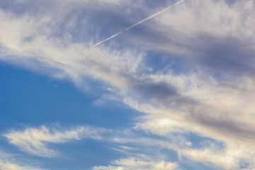 Blue sky with gray and white cirrus clouds at sunset