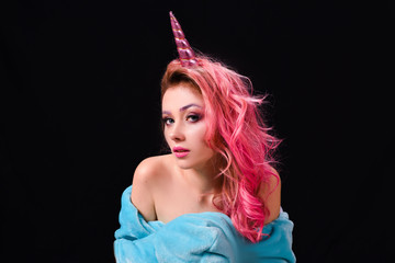 The Unicorn Girl. Young beautiful girl in the image of unicorn with pink hair and stylish make-up, copy space.