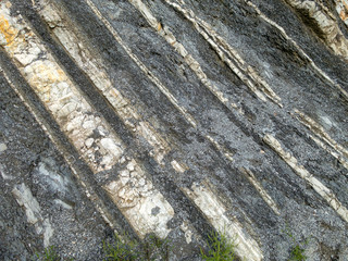 Mountain rock with gray, white and brown color stones diagonally arranged in strips. Background, macro, Caucasus