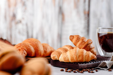 croissants in wooden plates with coffee on a light background