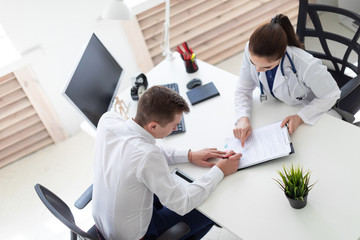 The young man at the doctor's office signs the documents.