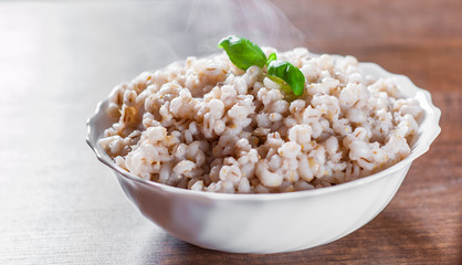 cooked pearl barley in bowl on a wooden table background