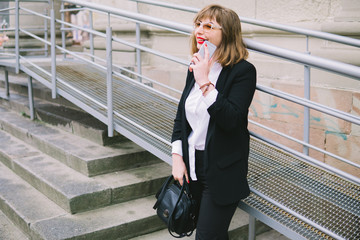 Fototapeta premium Business Women Style. Woman Going To Work Walking Downstairs. Portrait Of Beautiful Smiling Female In Stylish Office Clothes Going Old Town.