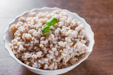 cooked pearl barley in bowl on a wooden table background