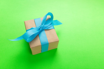 gift wrapped and decorated with blue bow on green background with copy space. Flat lay, top view
