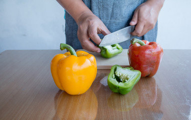Fresh colorful bell pepper cooking on wooden cut board in kitchen table ready for cook