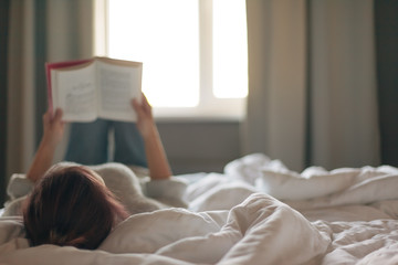 Girl reading a book in bedroom