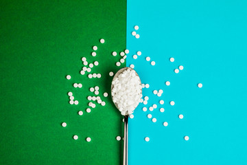Sugar-replacing tablets with a spoon on a green and blue background.