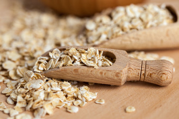 Fototapeta na wymiar Oat flakes in a wooden bowl with a scoop on the wooden board