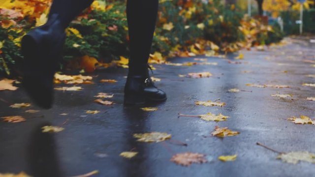 follow woman legs walking in autumn city in rainy day, fall season
