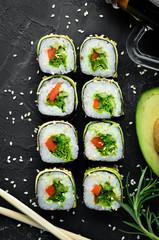 Sushi roll with avocado, cucumber and tomato. Japanese cuisine. Top view. On a black background.