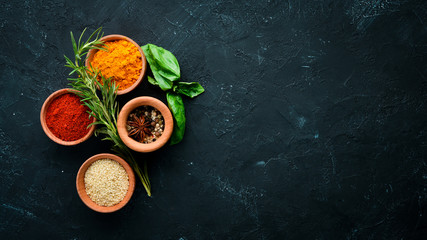 Colored spices on a black stone background. Free space for your text. Top view.