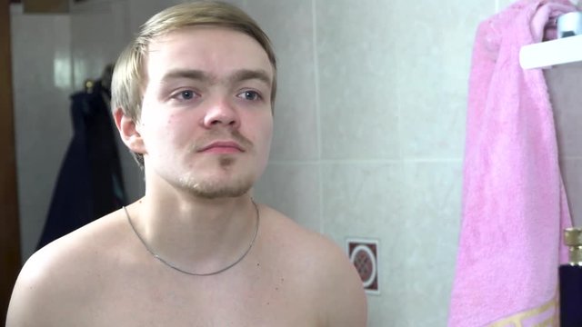 Handsome man using perfume in front of mirror. Handsome man applying perfume at the morning