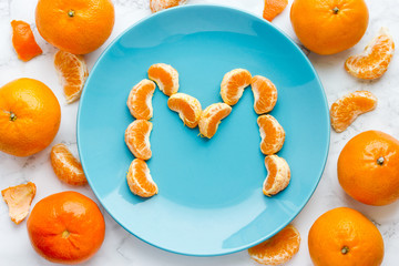 Fresh mandarin slices on blue plate letter m top view © san_ta