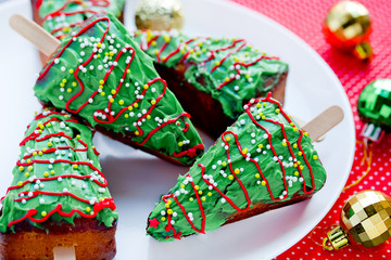 Christmas tree cakes, festive pie pieces decorated with green frosting and sprinkles, Christmas holiday winter treats for kids
