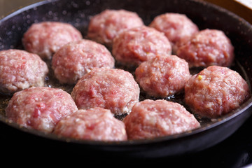 Fried meat patties are cooked in a pan in the oil in the kitchen with steam