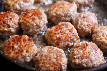 Fried meat patties are cooked in a pan in the oil in the kitchen with steam