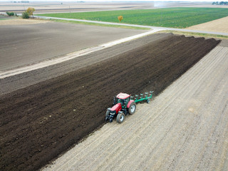 Air view of plowing red tractor on the field