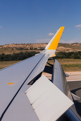 Fototapeta na wymiar Airplane wing on the runway at airport on a sunny day. Flaps up. Travel and holidays concept. view from the passengers window
