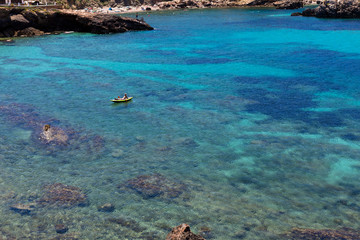 beautiful landscape in Ibiza of blue ocean in a sunny day with a man practicing paddle surf. Summer and holidays concept.