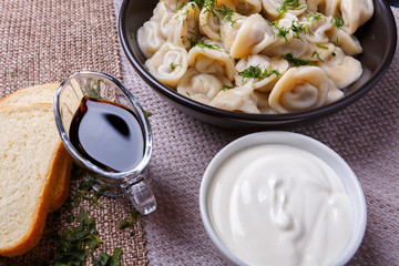 boiled dumplings national dish of many nations with sour cream, soy sauce and greens on the table