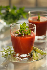 Tomato juice in a glass with parsley and celery, morning sun, healthy breakfast, selective focus