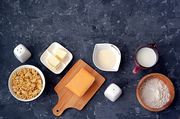 Ingredients for the preparation of macaroni and cheese: dry pasta, orange cheddar cheese, wheat flour, bread crumbs, milk, butter, salt, pepper