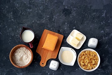 Ingredients for the preparation of macaroni and cheese: dry pasta, orange cheddar cheese, wheat flour, bread crumbs, milk, butter, salt, pepper