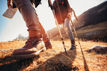 Hiking man and woman with trekking boots on the trail - obrazy, fototapety, plakaty