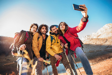 Group of hikers on a mountain at autumn day make selfie photo
