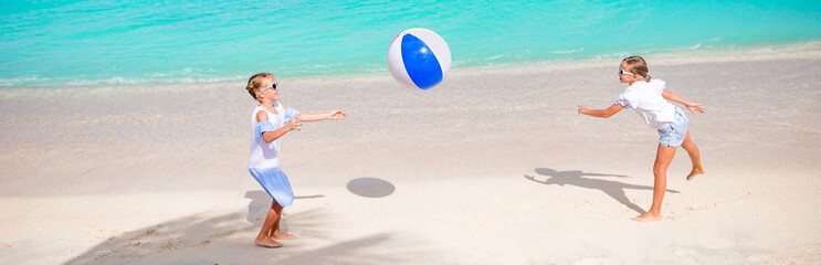Little adorable girls playing on beach with air ball