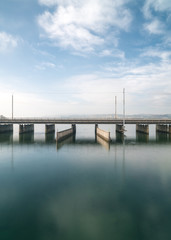 Fototapeta na wymiar vertical view of a concrete bridge over water with a train line and road running parallel and a boat and ship passageway below