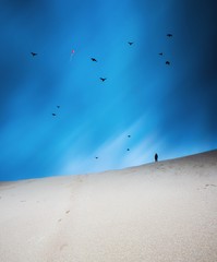Surreal landscape with sand dunes under and man silhouette