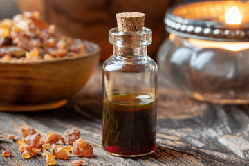 A bottle of myrrh essential oil with myrrh resin and a candle