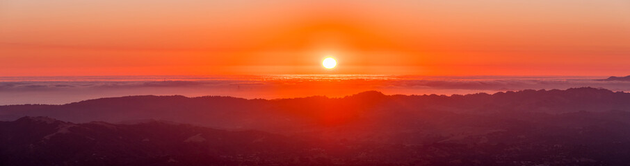 Fiery sunset over a sea of clouds as seen from the top of Mt Diablo, north San Francisco bay area, California (some of San Francisco's buildings visible under a layer of clouds)
