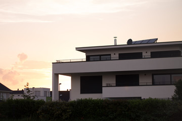 modern white house on the background of the sunset summer sky