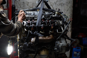 Car engine on crane hook in garage repair service, indoor