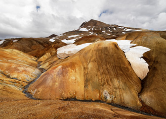 Landscape in ocher and brown tones with snowfields and a small river - Location: Iceland,...
