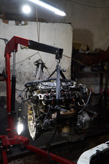 Fototapeta na wymiar Car engine on crane hook in garage repair service, indoor