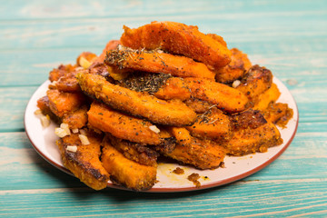 Chopped baked pumpkin with spices at blue background