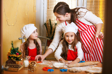 Merry Christmas and Happy Holidays. Family preparation holiday food. Mother and daughters cooking Christmas cookies.