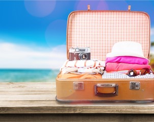 Retro luggage with colorful clothes on blurred background