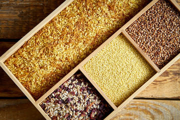 different, colorful types of groats in a wooden square box